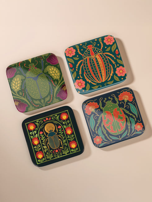 Set of 4 square Dark Academia Scarab Beetle Coasters, featuring detailed Gothic Botanical insect art prints in deep jewel tones. The hardboard coasters have a glossy finish and protective cork base. Premium Entomology Decor.